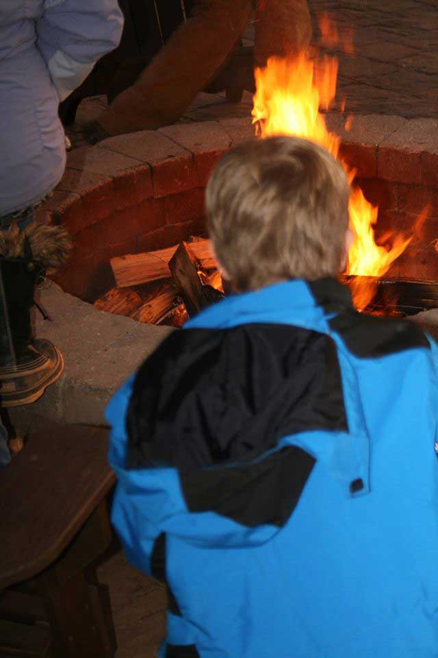 boy by fire pit with blazing fire