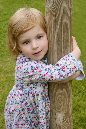 beautiful toddler hugging timber post