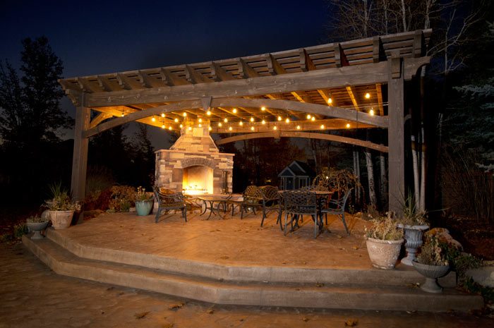 night time solid wood pergola with outdoor fireplace lights