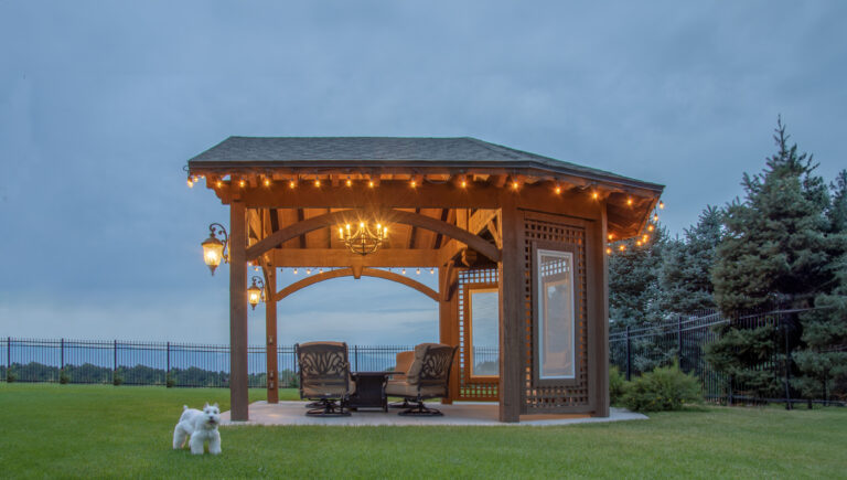 Timber frame pavilion with string lights, chandelier, and TimberVolt® power post at dusk