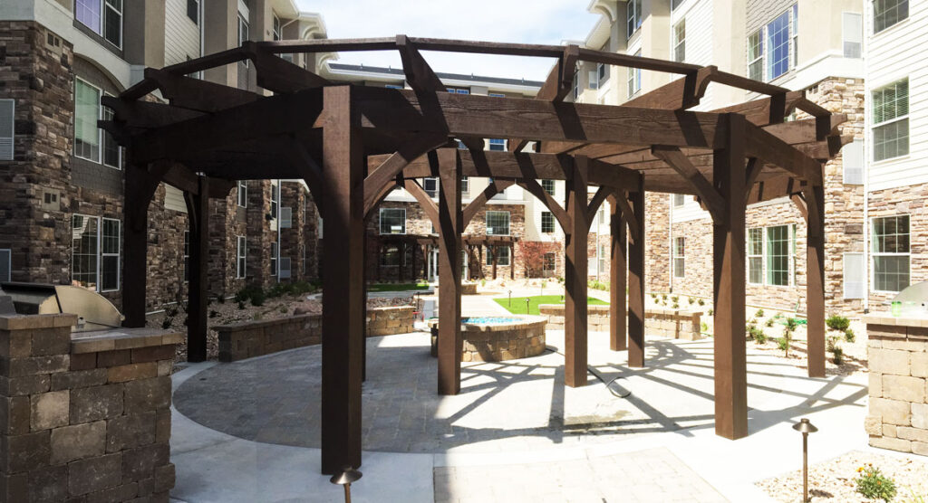 Timber frame pergola stained in Rich Cordoba at a luxury residential courtyard with stone architecture