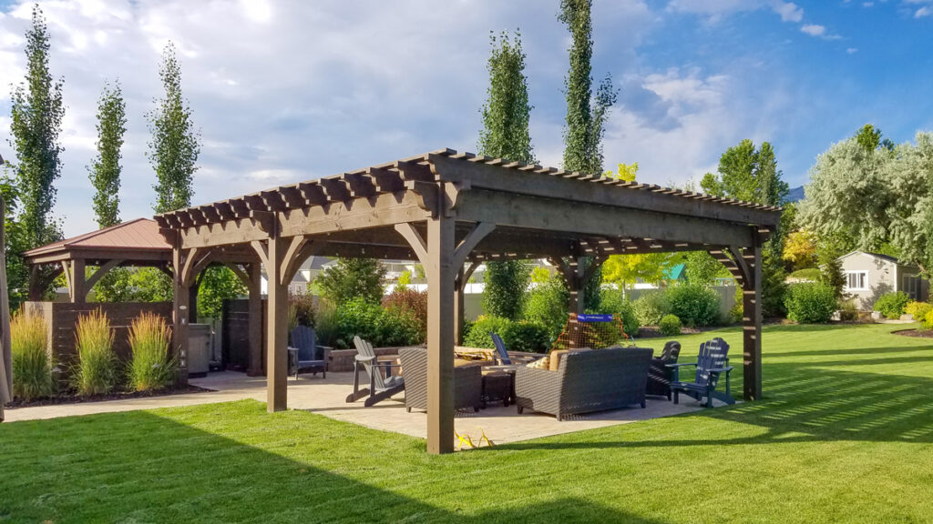 Large timber frame pergola stained in Rich Cordoba with a family gathered underneath in a backyard setting