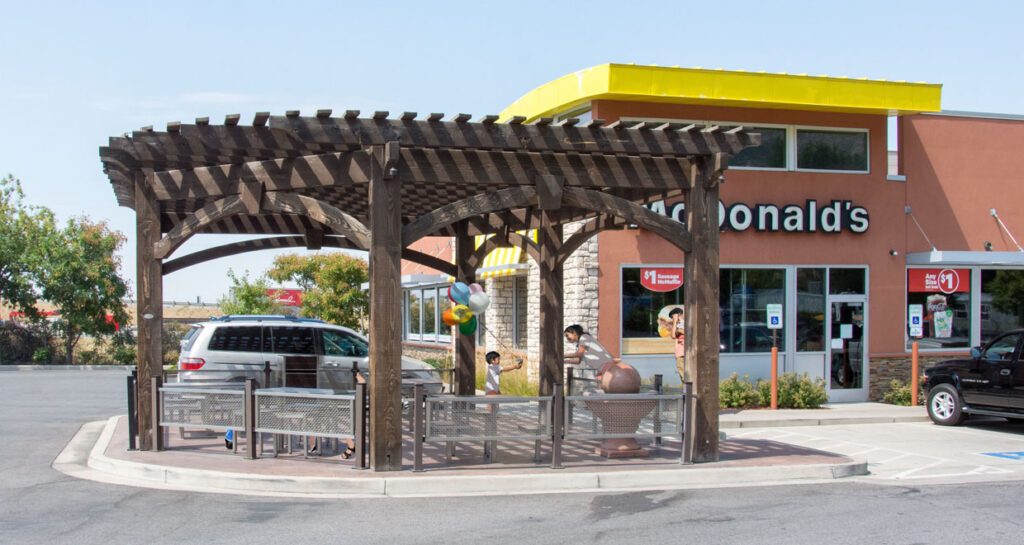 Timber frame pergola stained in Rich Cordoba installed at a McDonald’s outdoor dining area