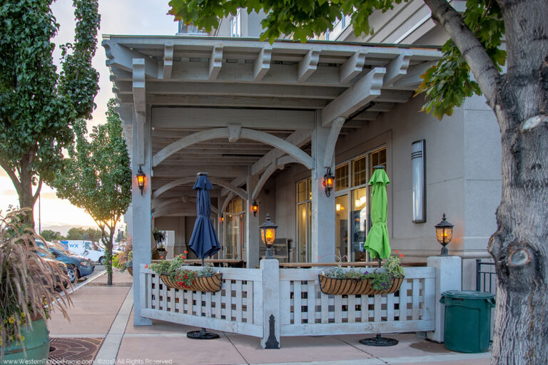 Timber frame pavilion by Western Timber Frame with TimberVolt® power posts, warm post lamps, and latticed fencing enclosing an inviting outdoor dining area.