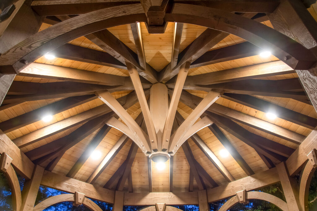View from beneath a timber frame gazebo by Western Timber Frame showcasing elegant roof design, lighting, and two-tone contrasting stain colors.