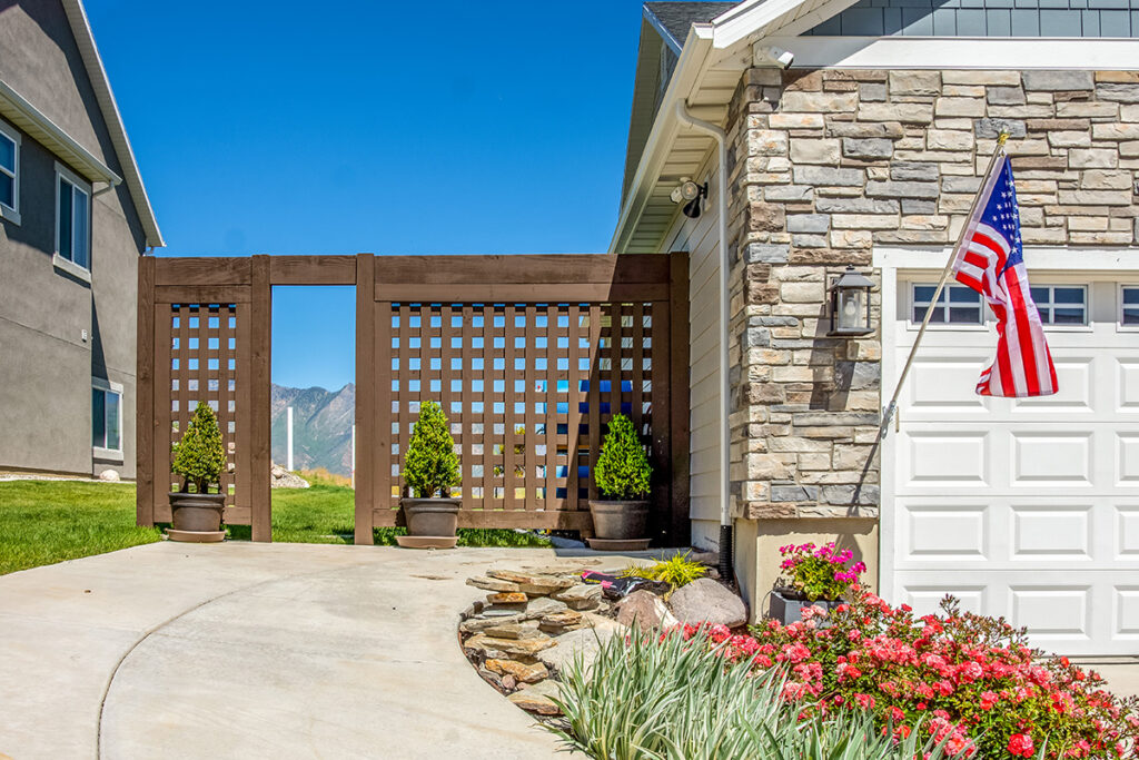 Western Timber Frame™ timber frame privacy screen with an open entryway, designed to shield side yard views and enhance curb appeal next to a driveway.
