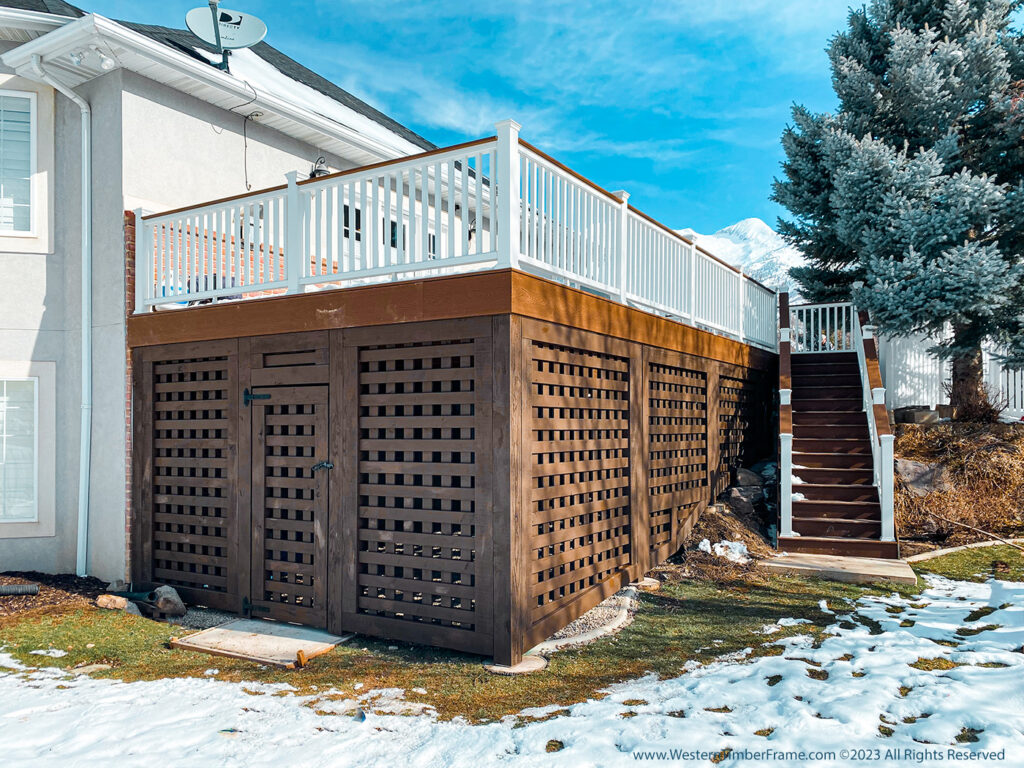 Western Timber Frame™ timber frame deck featuring white railing, dark-stained latticed privacy walls, and an enclosed storage area that allows light and ventilation underneath the structure.