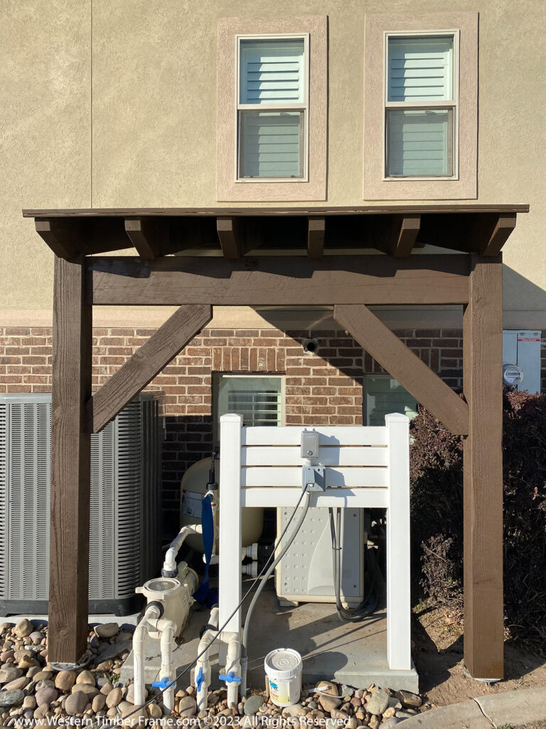 Western Timber Frame™ timber frame extension providing protective cover for home utilities, including HVAC and pool equipment.