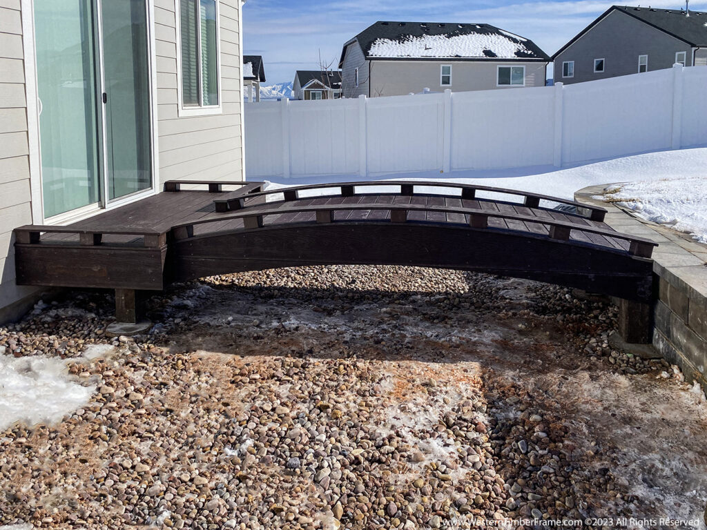 Western Timber Frame™ dark-stained timber frame deck and gently arched bridge, featuring an accessibility-enhanced design for safe, barrier-free outdoor transitions.