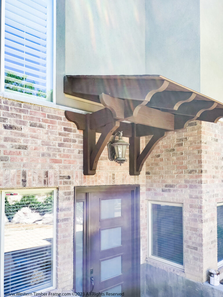 Western Timber Frame™ timber frame awning extending over a basement entryway, providing durable shade and protection.