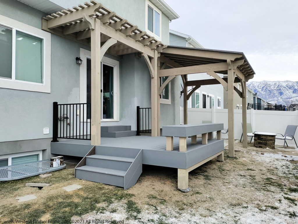 Western Timber Frame™ timber frame pergola and pavilion finished in Beach Sand and Gray stain, installed over a custom deck with a built-in bench and a backyard fire pit.