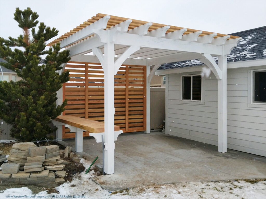 Western Timber Frame™ pergola featuring an Alpine White frame with natural wood roof accents, a TimberVolt® power post, horizontal privacy slat wall, and built-in timber bench.