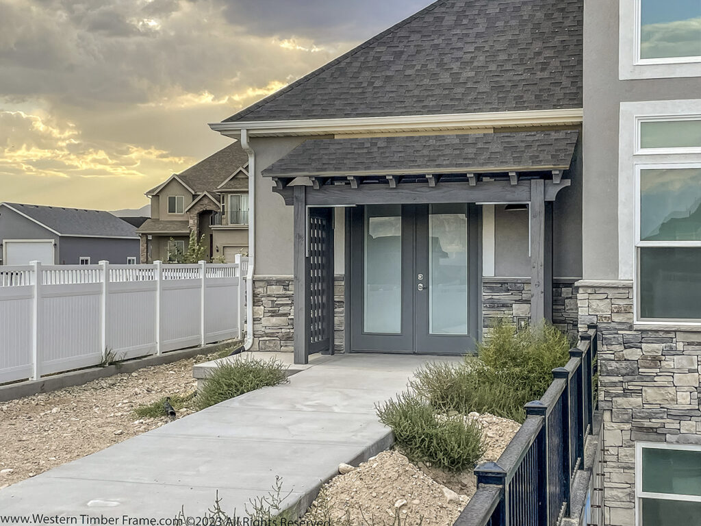 Timber frame timber porch cover by Western Timber Frame™ with lattice privacy side panels and matching gray-toned finish, installed over a front entryway.