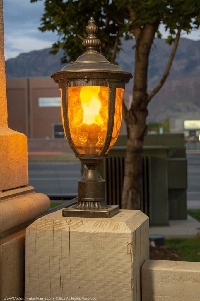 Western Timber Frame timber frame pergola post featuring TimberVolt® integrated power and elegant lamps mounted on top, lighting a commercial outdoor dining area.