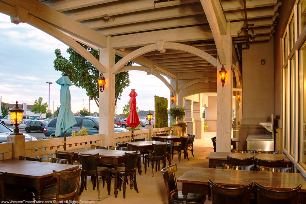 Western Timber Frame commercial timber frame pergola featuring TimberVolt® integrated power system and post-mounted lamps over a vibrant outdoor dining area.
