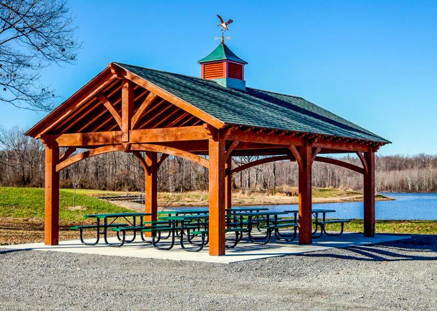 Timber frame lakeside park pavilion in Kentucky with cupola and picnic tables underneath by Western Timber Frame