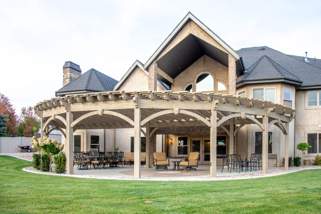 Expansive round timber pergola with natural finish over a patio at a luxury home.