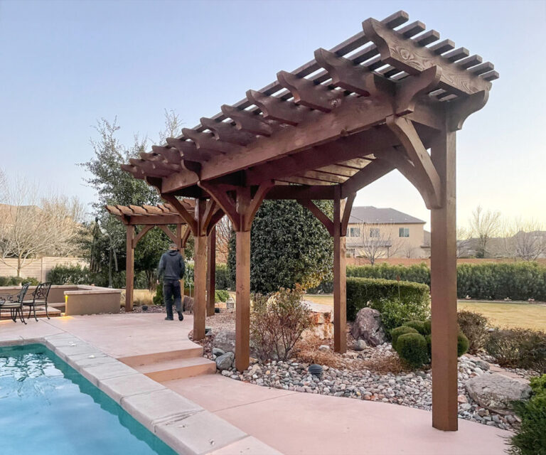 Timber frame trellis-style pergola beside a backyard pool with a person walking toward the patio