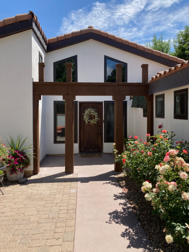 Western Timber Frame™ timber frame entryway structure with decorative post and beam detailing, enhancing the front entrance of a white stucco home
