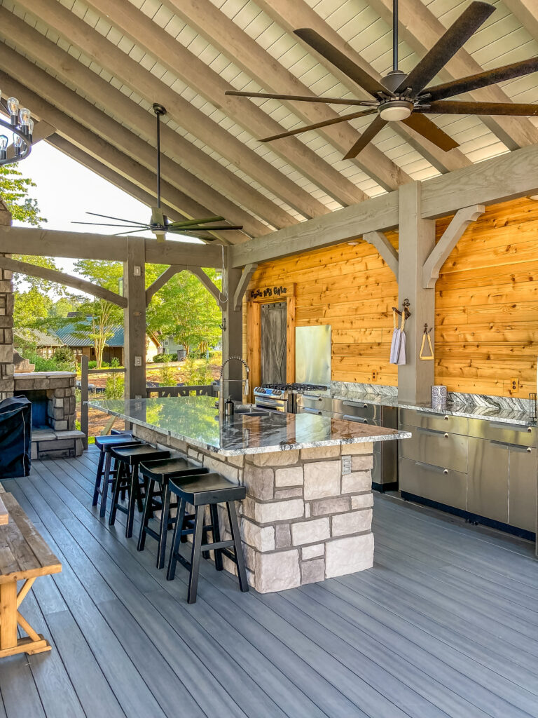 Western Timber Frame™ timber pavilion deck with outdoor kitchen installed in a public recreational park in Ohio, featuring exposed wood beams, stone countertops, and ample space for outdoor gatherings and cooking.