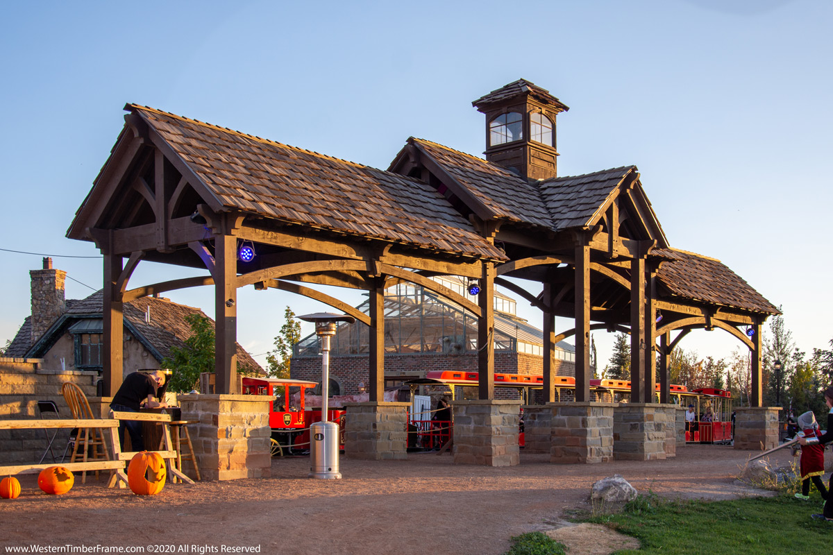 Wooden structure with a clock tower, stone columns, and a gravel path