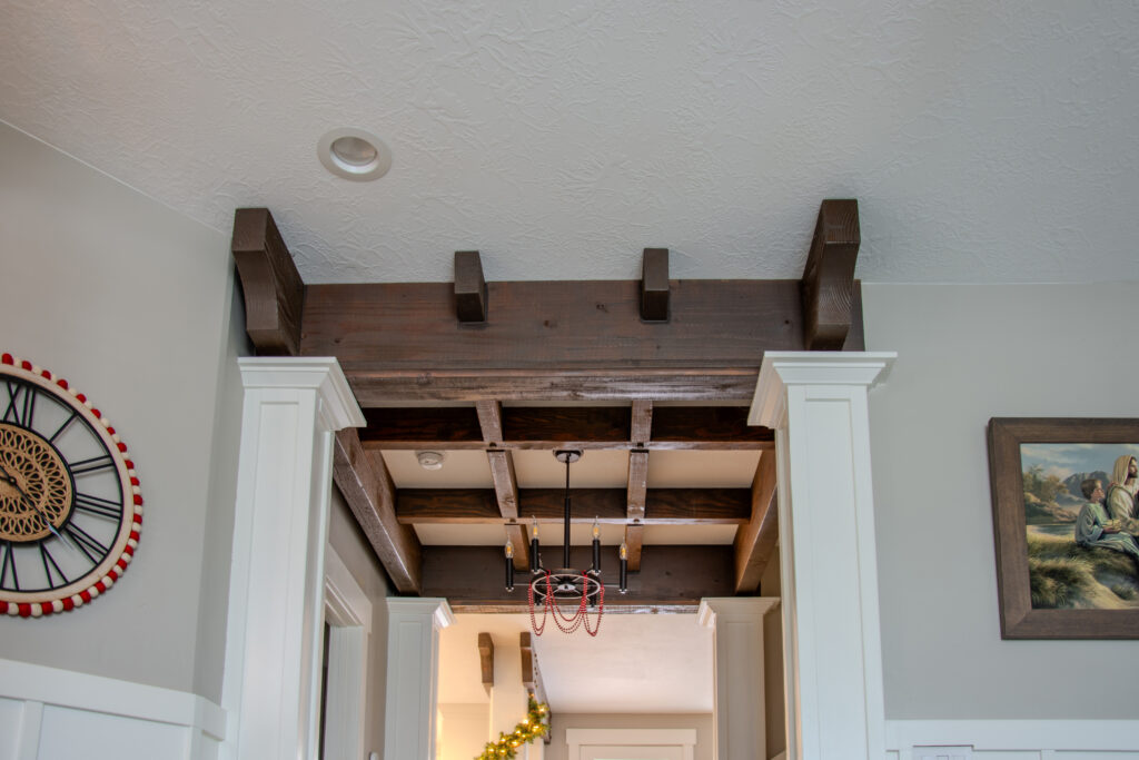 Decorative interior timber ceiling grid with exposed beams by Western Timber Frame™, installed above a hallway entry with white trim and crown molding