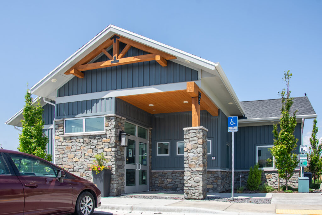 Timber frame gable truss and entry posts by Western Timber Frame™ featured on the exterior of Traverse Mountain Pet Care, a modern commercial building with stone and board-and-batten siding