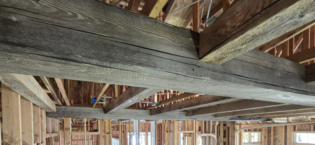 Reclaimed heavy timber beams by Western Timber Frame™ being installed during new commercial construction, blending historic character with modern craftsmanship.