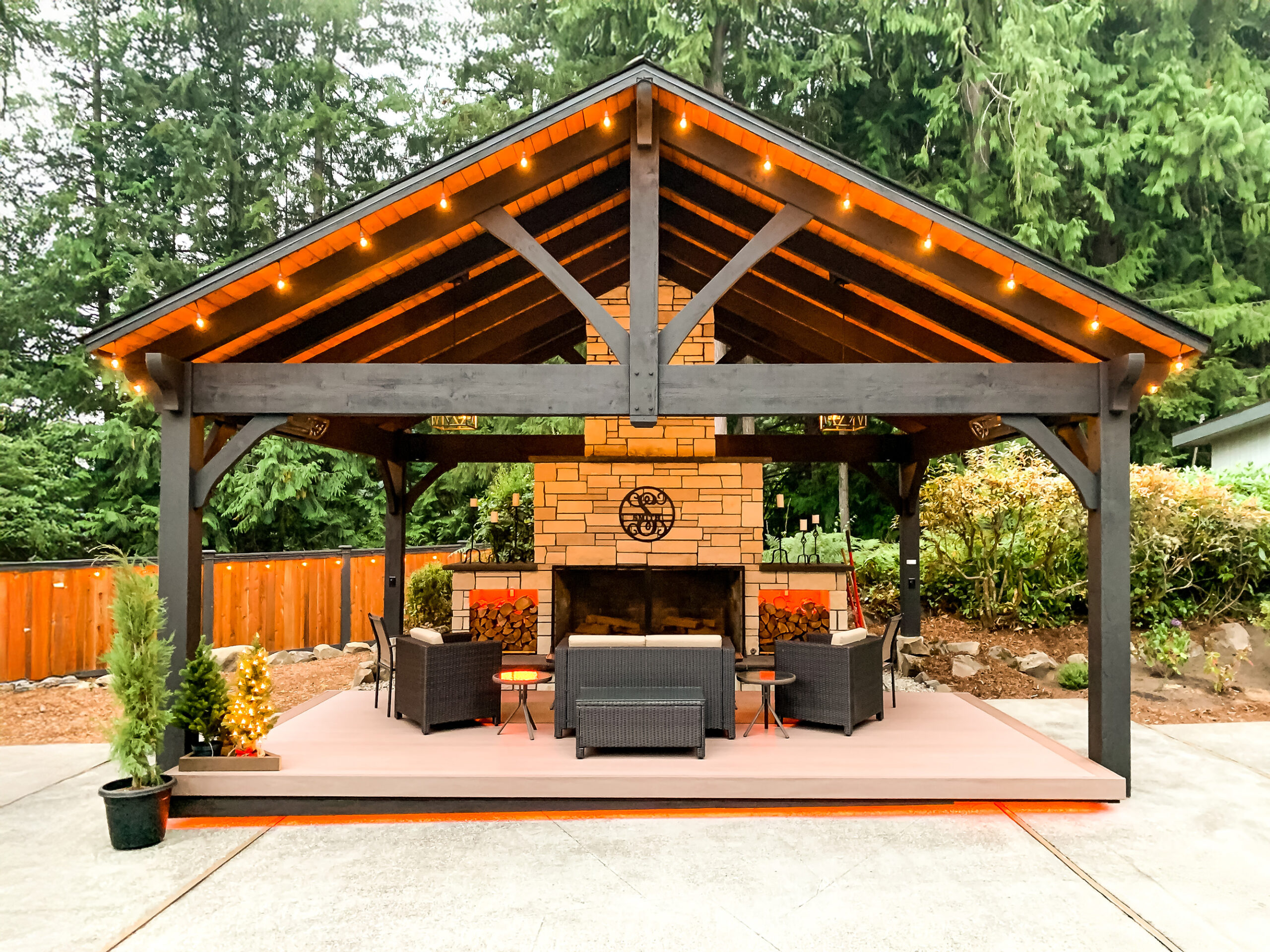 TimberVolt® powered pavilion with fireplace and string lights in woodland setting