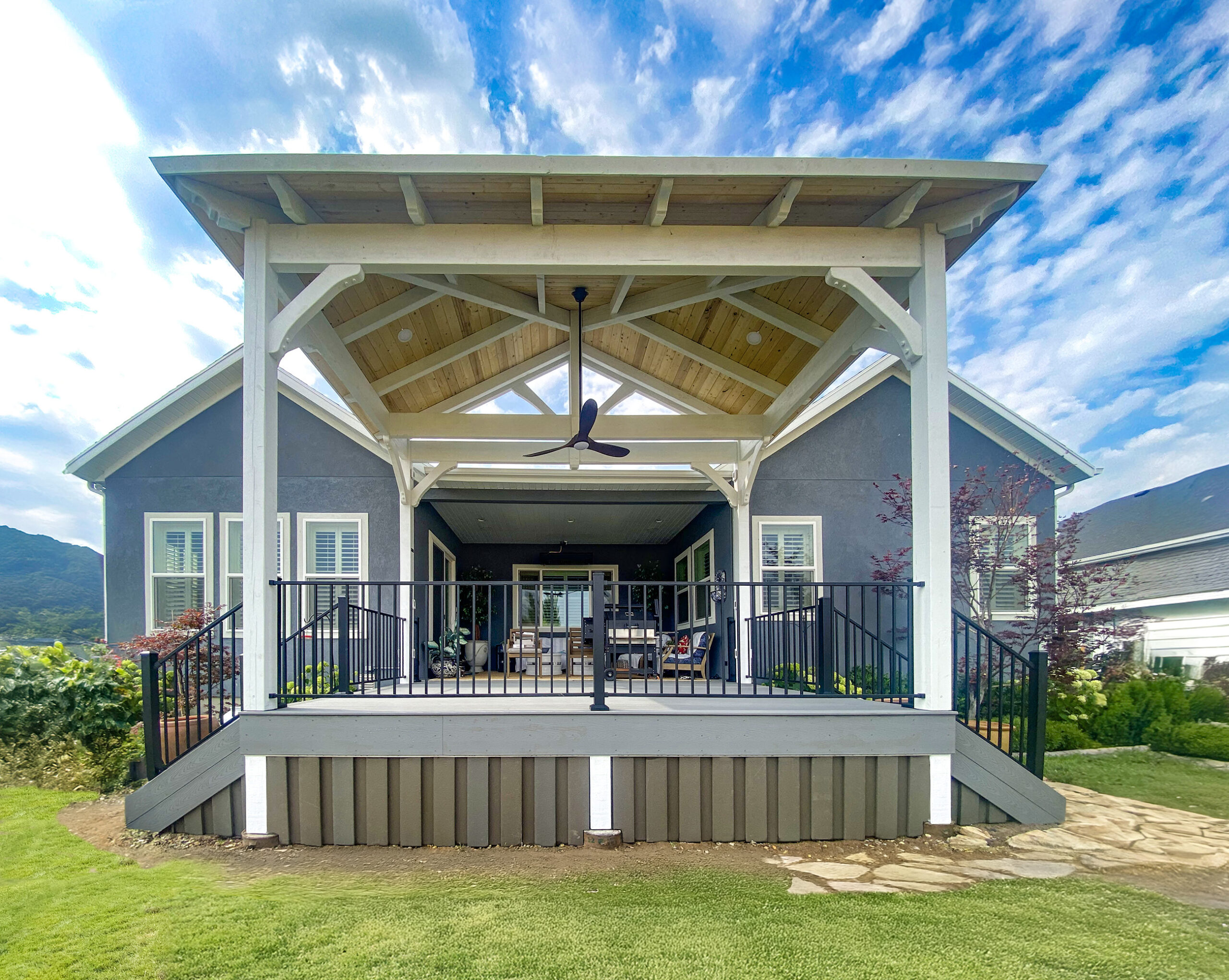 Expanded backyard deck with custom hipped roof timber pavilion bright tongue and groove ceiling TimberVolt power posts and black railings