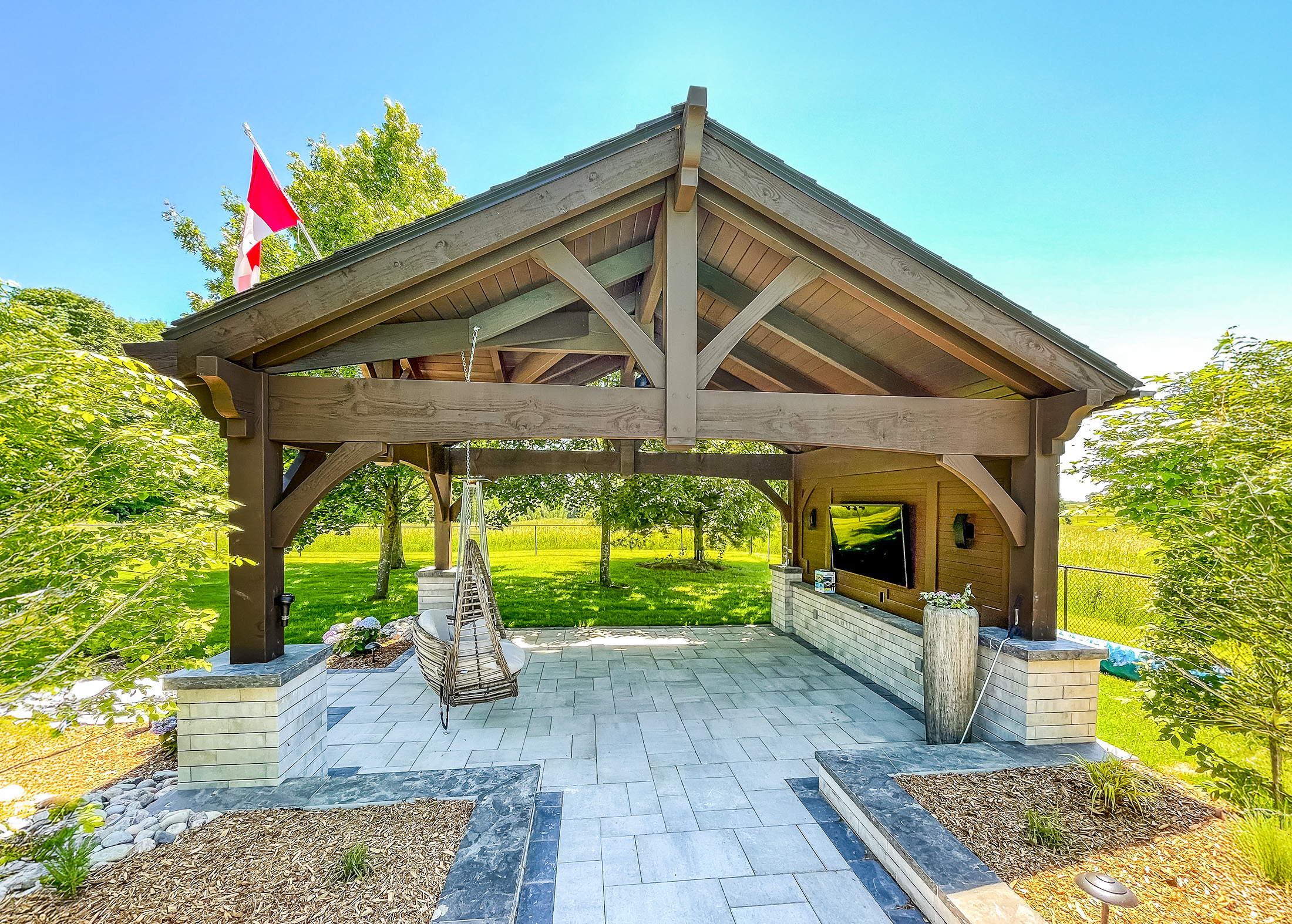 Canadian timber pavilion with TV wall, lounge seating, and Canadian flag above roofline.