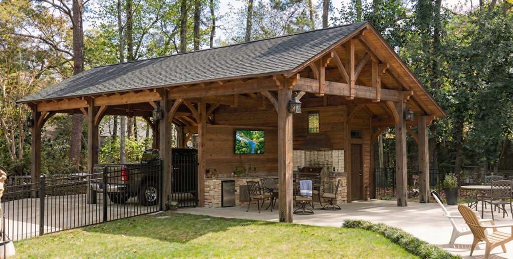 Timber frame carport with enclosed outdoor living space and vehicle parking beside backyard pavilion