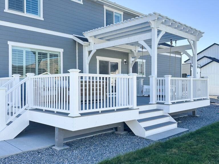 Backyard timber frame deck with white railing, pergola, and swing installed after renovation