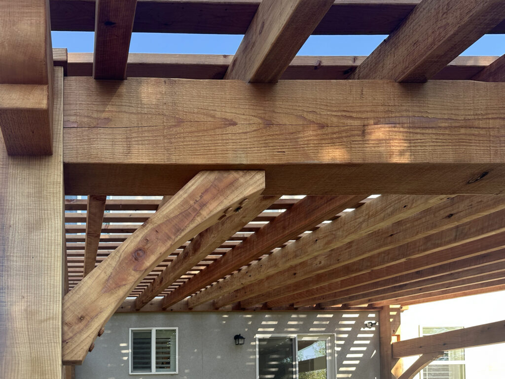 Close-up of redwood timber frame pergola beams and dovetail joinery.