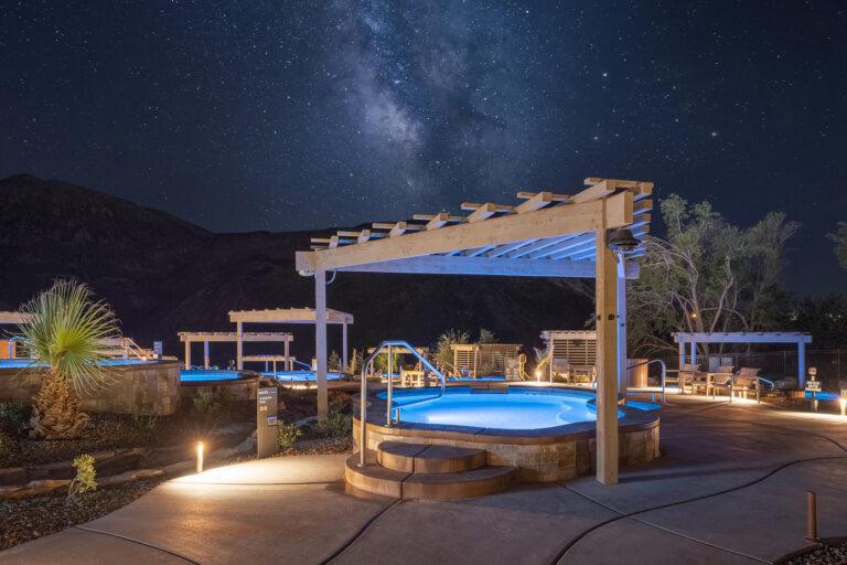Timber frame pergola over glowing hot spring pool at Zion Canyon Hot Springs under the Milky Way night sky