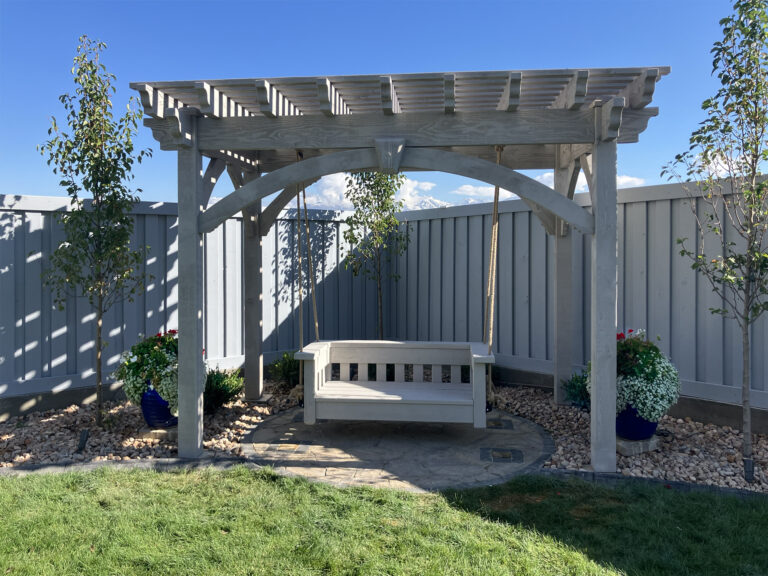 After photo showing a handcrafted Douglas Fir pergola with arched knee braces and matching timber swing installed by Western Timber Frame to create a peaceful backyard retreat.