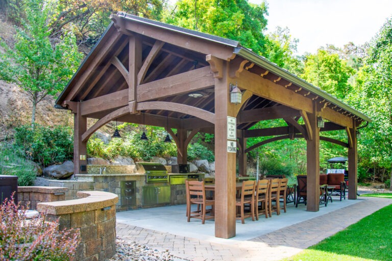 Heavy timber pavilion 10 years after installation with arched knee braces, tight joinery, and weathered stain in canyon setting