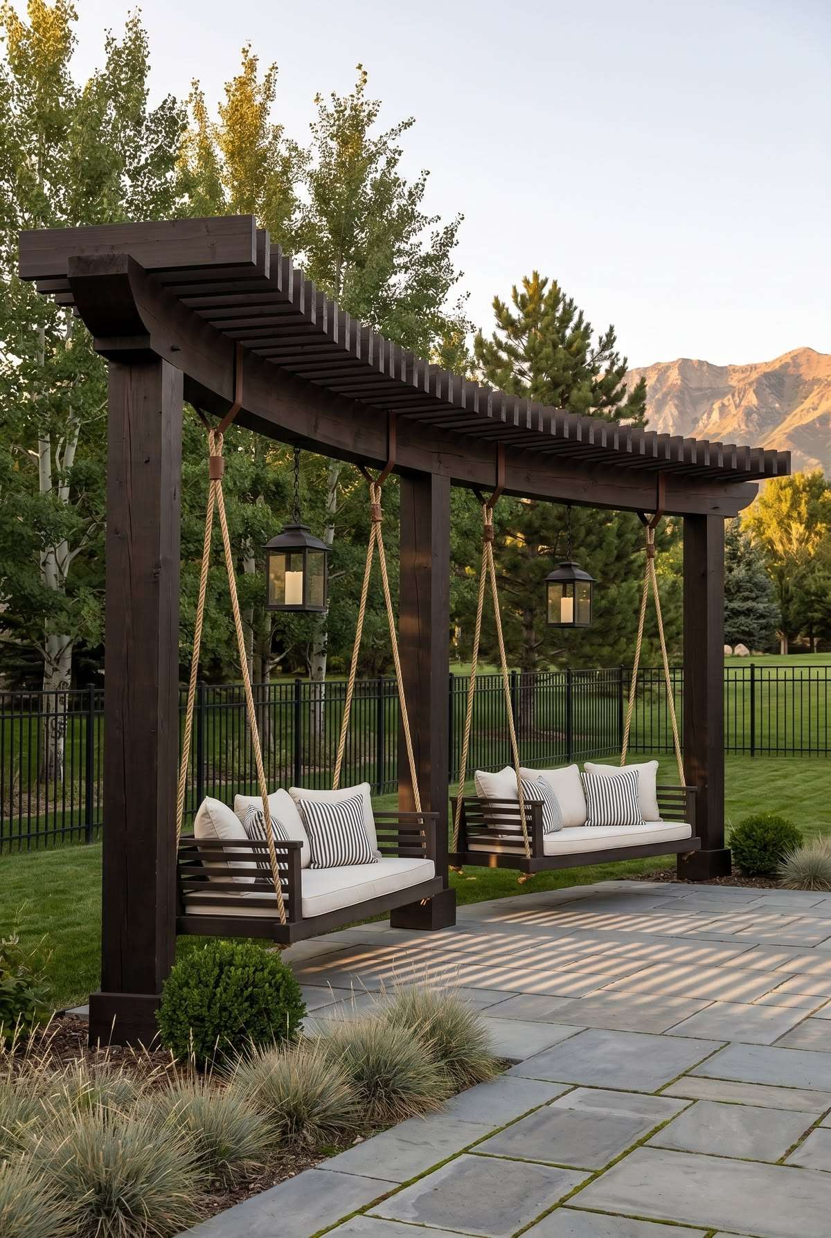 Dark stained swing pergola with hanging bed swings and a privacy panel beside the seating