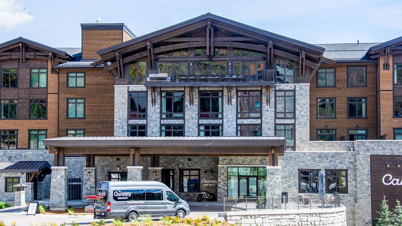 Main hotel gable with a heavy timber king post truss, corbels, and brackets framing a top-floor balcony