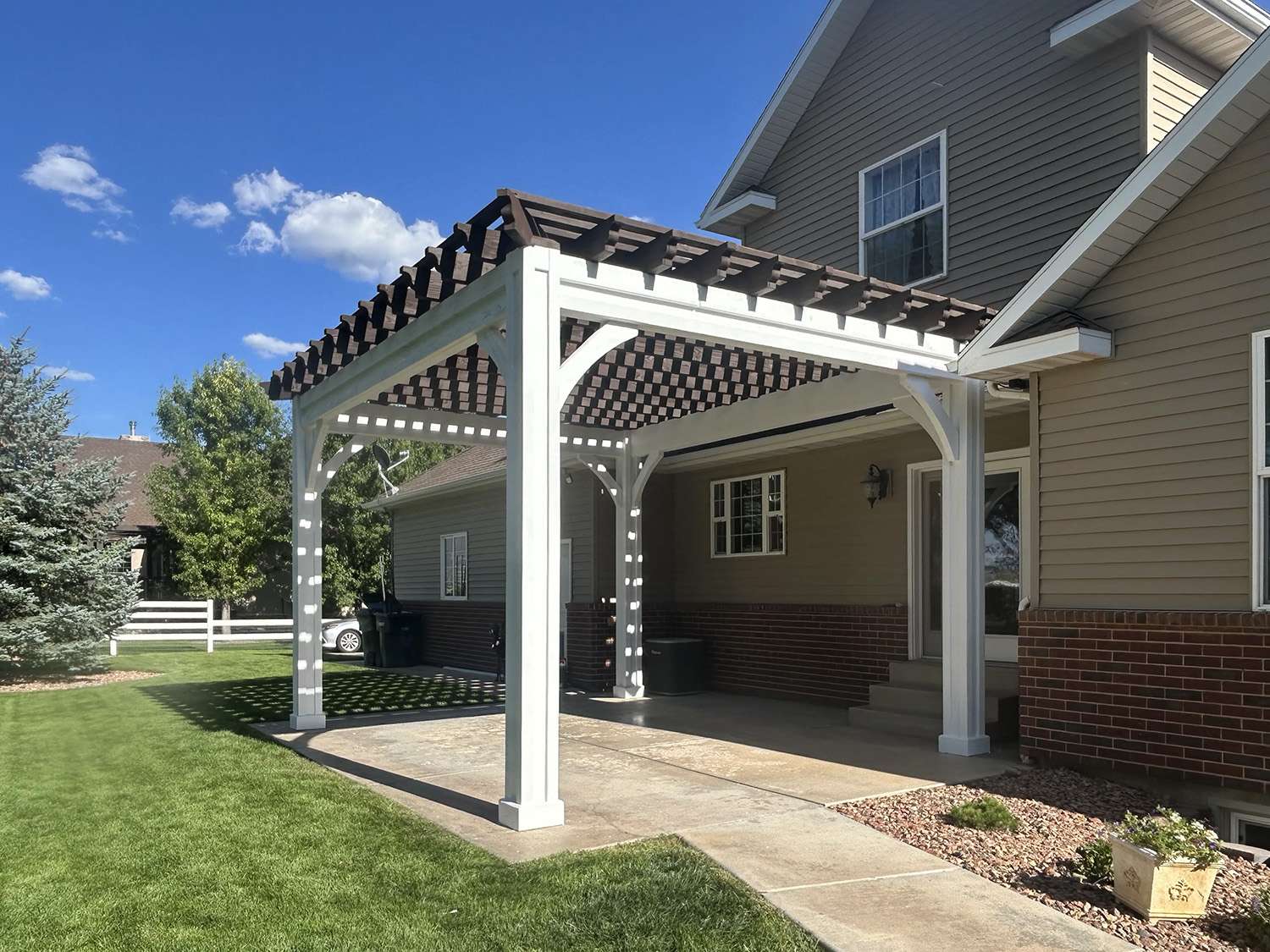 Two-tone Western Timber Frame California pergola attached to a house, with white posts and beams supporting dark-stained rafters and top slats